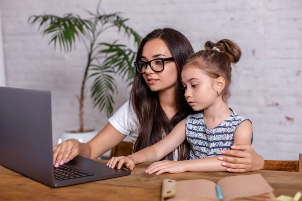 eine junge Mutter mit kleiner Tochter kauft am PC im Internet ein - Foto, Bild