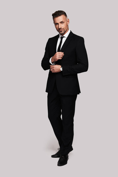 Confident and handsome man in full suit adjusting sleeve   - Фото, изображение