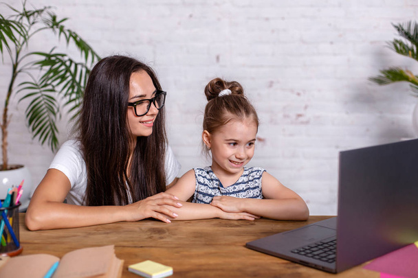 Молодая мать с маленькой дочерью делают покупки в Интернете за персональным компьютером
 - Фото, изображение