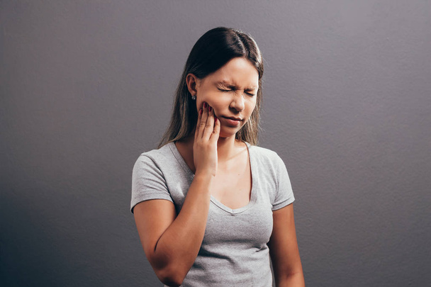 unhappy woman feel pain on her teeth isolated on gray background - Φωτογραφία, εικόνα