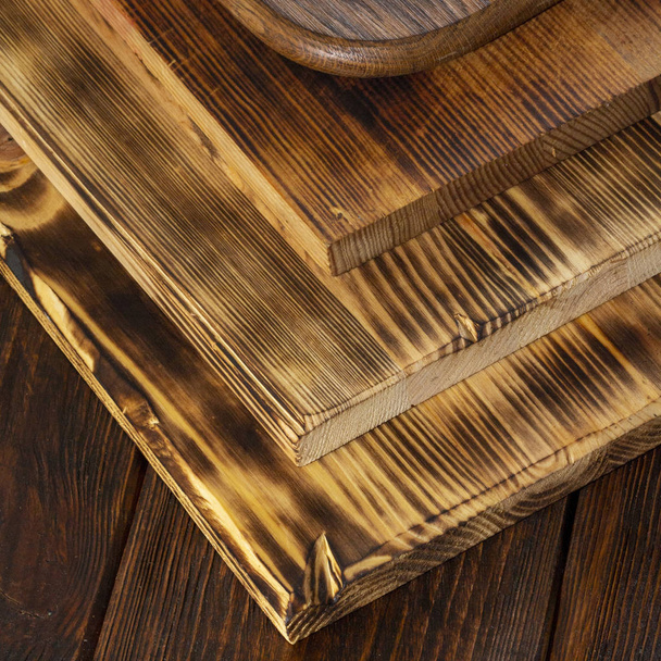 selectieve aandacht van stapel verschillende houten snijplanken op oude houten tafel - Foto, afbeelding