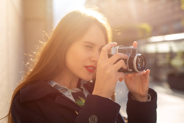Outdoor autumn smiling lifestyle portrait of pretty young woman, having fun in the city with camera, travel photo of photographer. - Photo, Image
