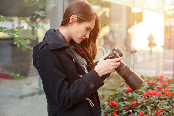 Portrait of professional female photographer on the street photographing on a camera. - Photo, image