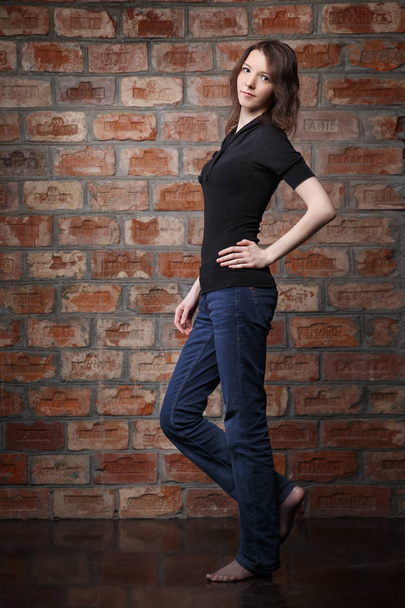 young woman in casual clothes posing on brick wall background - Fotó, kép