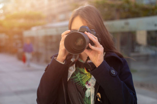 Attractive tourist woman photographer with camera, outdoor in city street. Sun flare - 写真・画像