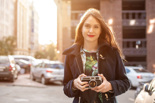 Outdoor autumn smiling lifestyle portrait of pretty young woman, having fun in the city with camera, travel photo of photographer. - Фото, зображення