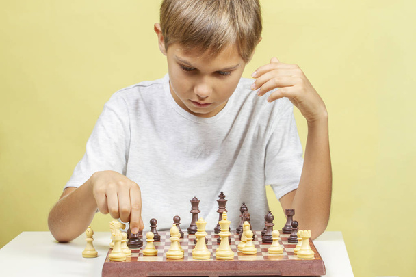 Kind beim Schachspielen. Junge schaut auf Schachbrett und denkt über seine Strategie nach. - Foto, Bild