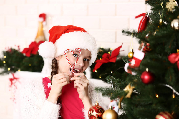 Young girl with candies near christmas tree at home - Foto, Imagem
