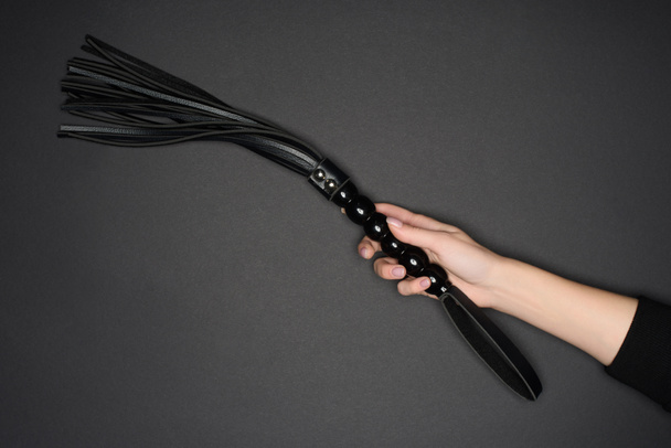 обрізаний вид жіночої руки, що тримає знущання над батогом ізольовано на сірому
 - Фото, зображення