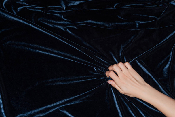 περικοπεί θέα γυναικείο χέρι που κρατά σφιχτά ύφασμα σκούρο βελούδο - Φωτογραφία, εικόνα