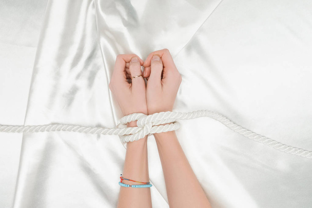 pohled shora ženských rukou ohraničena provazem saténovou látkou na pozadí - Fotografie, Obrázek