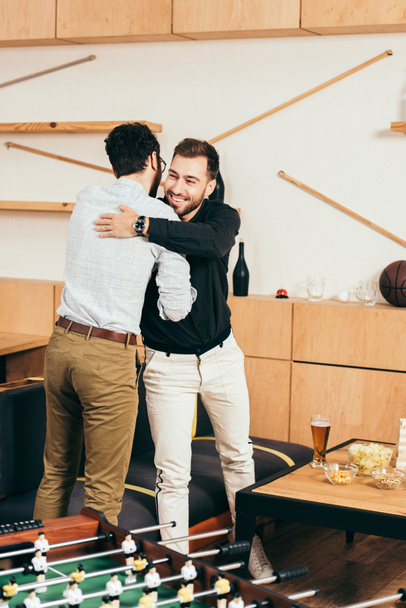 Друзья обнимаются, приветствуя друг друга в кафе
 - Фото, изображение