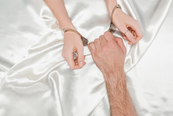 cropped view of male hand holding handcuffs on woman hands - Foto, imagen