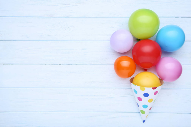 Colorful balloons with birthday paper cap on wooden table - Foto, afbeelding