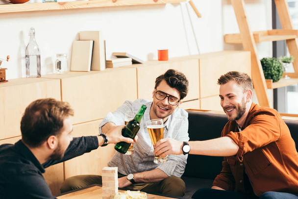 smiling friends clinking drinks while resting in cafe together - Photo, Image