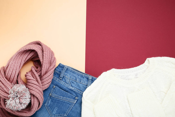 Folded sweater with jeans and scarf on colorful background - Photo, image
