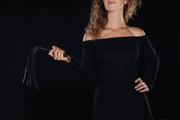 kısmi deri kırbaç tutan kadın görünümünü el izole üzerinde siyah kırbaç - Fotoğraf, Görsel
