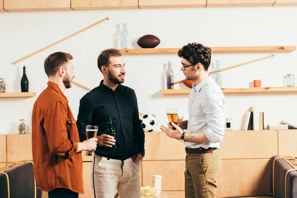 hommes avec de la bière dans les mains parler tout en se reposant dans le café
 - Photo, image