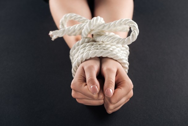 cropped view of female bound hands with rope isolated on black - Zdjęcie, obraz