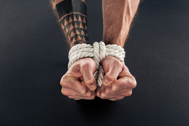 cropped view of bound male hands with tattoo isolated on black - Photo, Image
