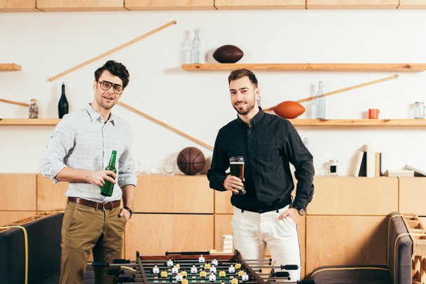portrait of young men with beer standing at table soccer in cafe - Photo, Image
