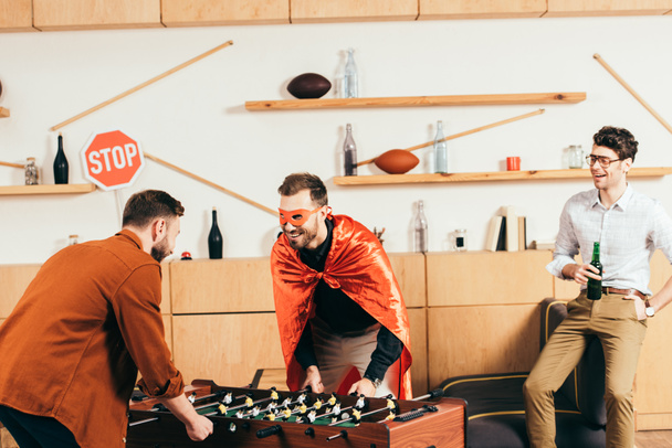 mladí veselí přátelé hrát stolní fotbal spolu v kavárně - Fotografie, Obrázek