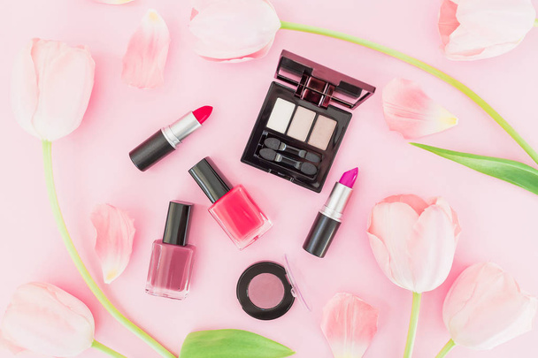 Composición femenina con flores de tulipanes y cosméticos de maquillaje sobre fondo rosa. Vista superior. Puesta plana
. - Foto, Imagen