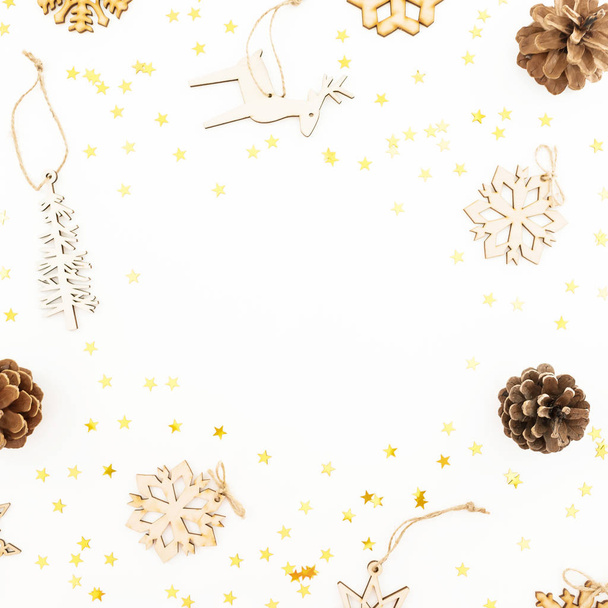 Christmas pattern with wooden tree decoration, snowflakes and pine cones on white. Flat lay, top view. Winter festive frame. - Photo, Image