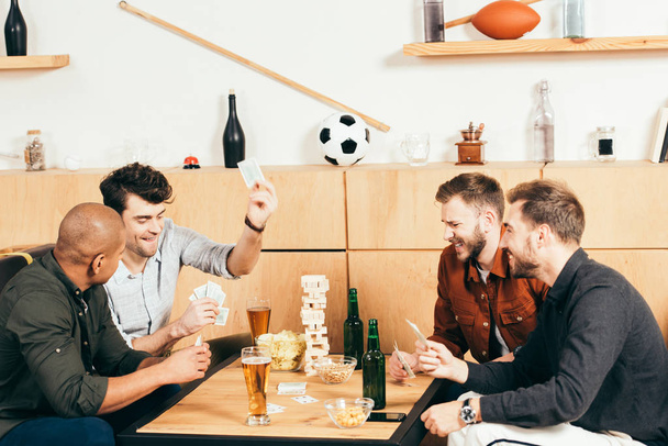 multiculturele mannen speelkaarten terwijl het besteden van de tijd samen in café - Foto, afbeelding