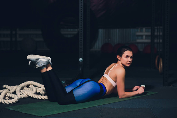 Fit young woman lying on exercise mat doing stomach exercises. - 写真・画像