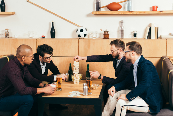 homens de negócios multiétnicos com cerveja jogando blocos de madeira jogo no café
 - Foto, Imagem
