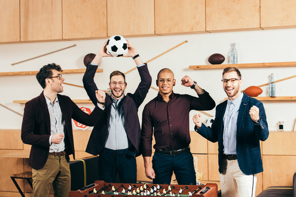 portrait of happy multiracial business team with soccer ball gesturing in cafe - Photo, Image