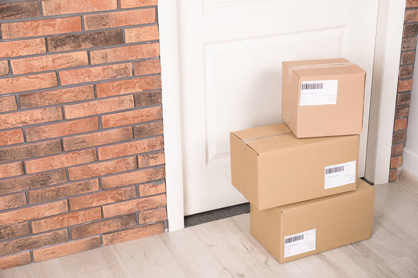 Cardboard parcel boxes on floor near apartment entrance. Mockup for design - Φωτογραφία, εικόνα