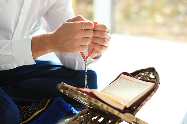Muslim man with Koran and misbaha praying indoors, closeup - Фото, изображение