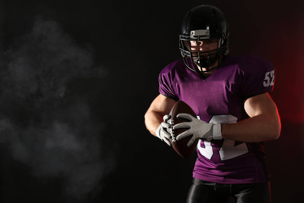 American football player with ball on dark background. Space for text - Foto, immagini