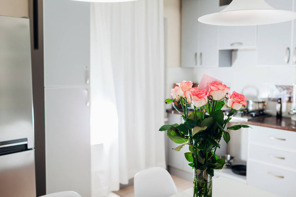 Bouquet of roses with card left on kitchen. Modern kitchen design. Interior of kitchen decorated with flowers. - Photo, Image
