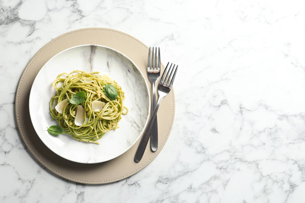 flache Liegekomposition mit einem Teller köstlicher Basilikum-Pesto-Pasta und Platz für Text auf einem Marmortisch - Foto, Bild
