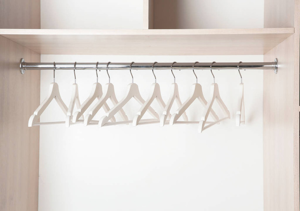 Clothes rail with wooden hangers in wardrobe - Foto, afbeelding