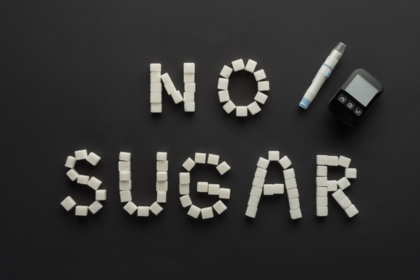 "kein Zucker "Schriftzug aus Würfeln mit medizinischem Gerät auf schwarz  - Foto, Bild