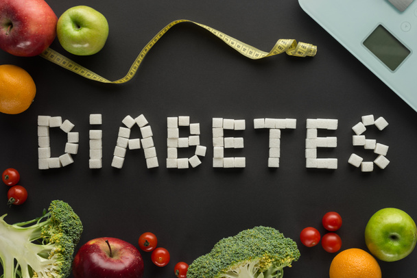 "diabetes"word gemaakt van suikerklontjes met schubben op zwarte achtergrond - Foto, afbeelding