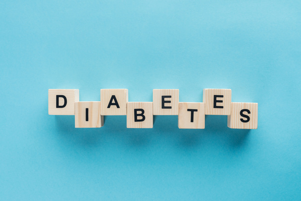 top view of "diabetes" lettering made of wooden cubes on blue background - Photo, Image