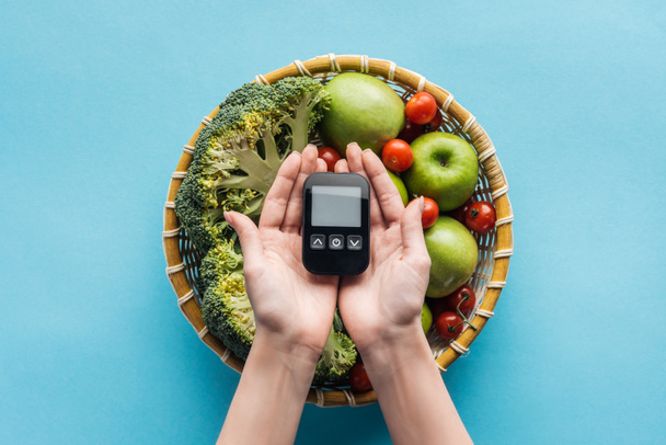 vista dall'alto del glucometro in mani femminili con verdure e mele su sfondo blu
 - Foto, immagini
