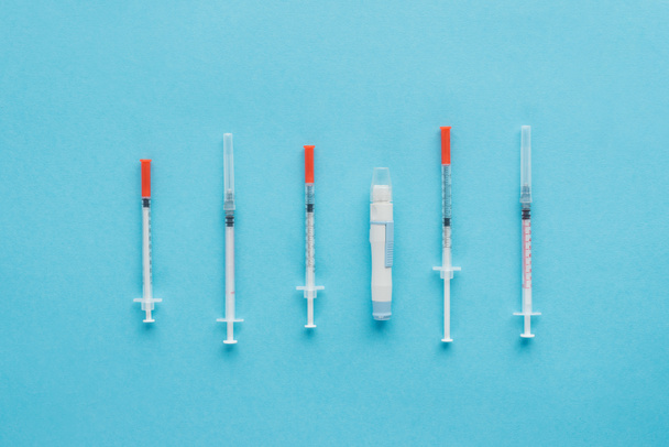 vista superior das seringas de insulina para diabetes no fundo azul
 - Foto, Imagem