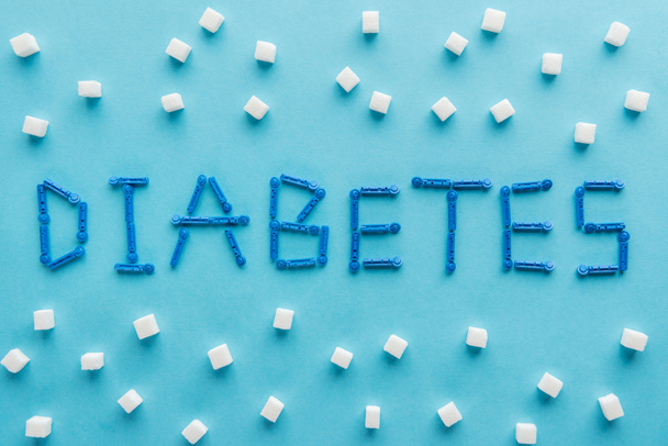 "Diabetes "Wort aus Wegwerfnadeln mit Zuckerwürfeln auf blauem Hintergrund - Foto, Bild