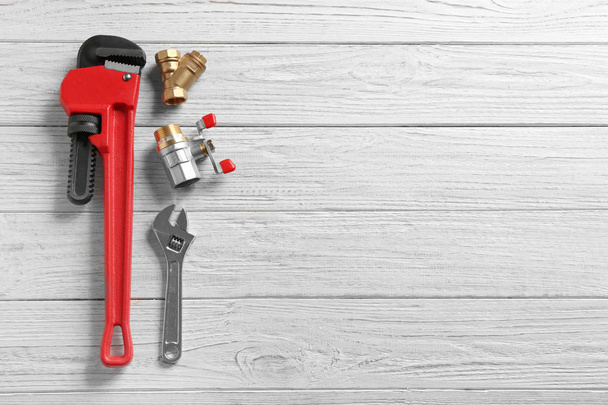 Flat lay composition with plumber's tools and space for text on wooden background - 写真・画像