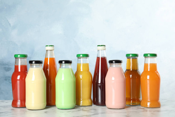 Bottles with different drinks on table against color background - Photo, image