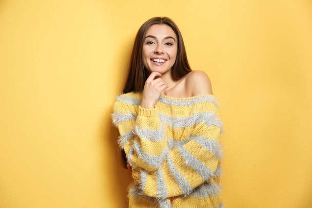 Beautiful young woman in warm sweater on color background - Fotó, kép