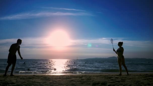 silhouettes. people play badminton on the beach at sunset. - Footage, Video