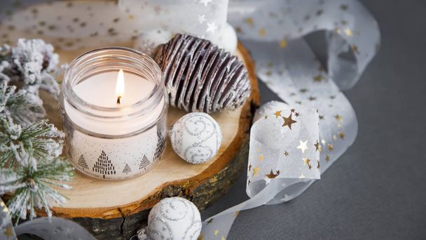 Festive Christmas white candle with ribbon, globes, pine cones a - 写真・画像