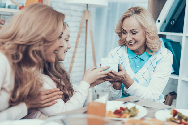 Family Celebrating Grandmother's Birthday at Home. Cake on Table. Happy Family. Mother with Daughter. Smiling Women. Smiling Grandmother. Celebration Concept. Glass of Wine. Giving Gift Box. - Foto, imagen